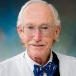 Dr. Mike Malloy in a white lab coat with glasses and a bow tie.