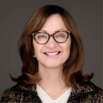 Jenny Mladenovic, MD, MBA, MACP is smiling and where glasses in this professional looking head shot.