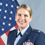 Dr. Burtson head shot wearing her uniform ( a colonel in the United States Air Force Medical Corps) with the American flag behind her.